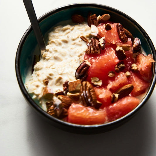 Schale mit Haferflocken, Grapefruit und Nüssen im weichen Morgenlicht